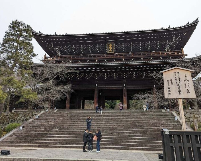 A traditional Japanese building with a curved roof and a signboard in front. 2