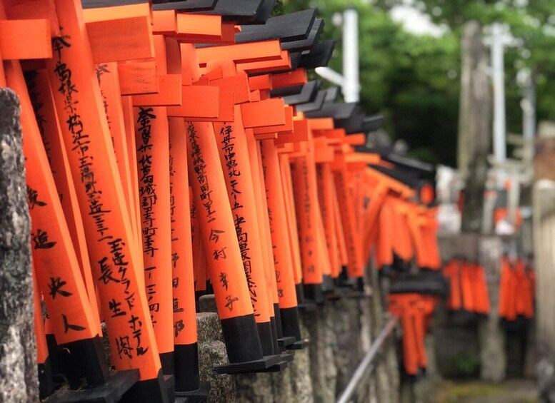 A row of orange torii gates with black tops, leading to a shrine. 1