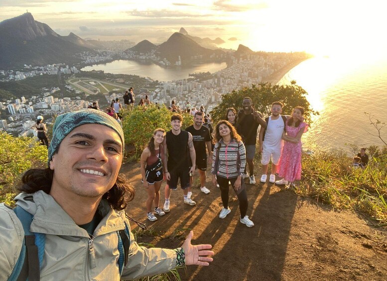 A group of people standing on a hill overlooking a city with a river and mountains in the background. 5