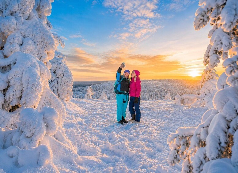 Two people taking a selfie in a snowy landscape with a sunset in the background. 1