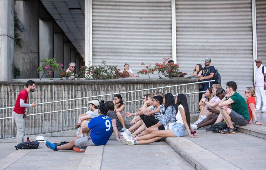 People sitting on steps, a man in a red shirt gesturing, and a person in a blue shirt with the number 9. 5