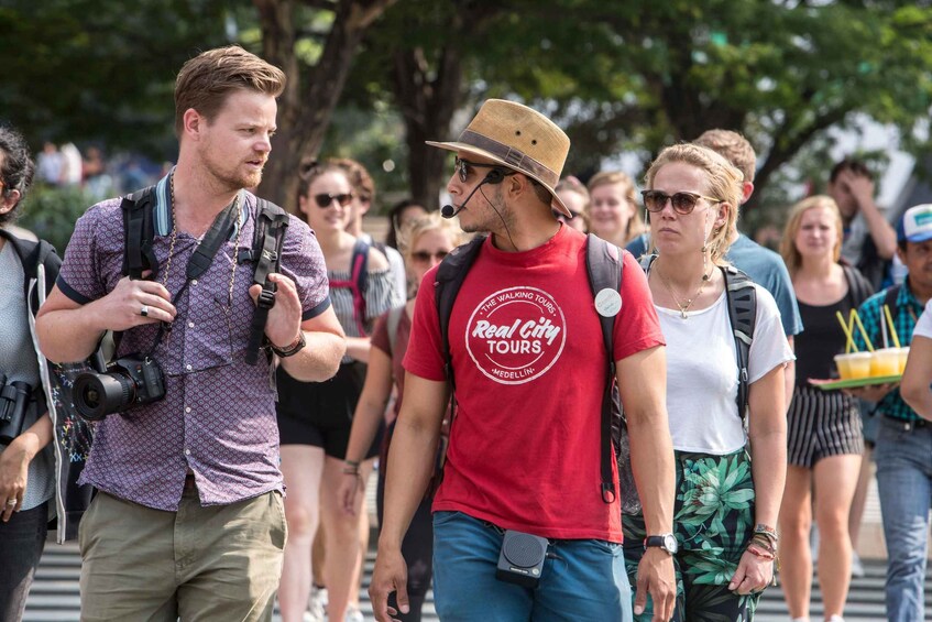 A group of people walking outdoors, some carrying backpacks and cameras. 2