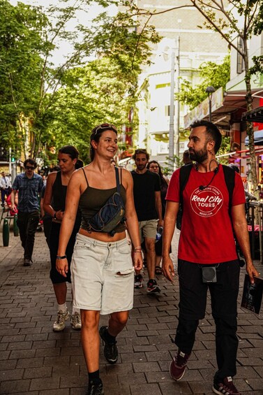 A group of people walking on a city street with trees and buildings in the background. 3