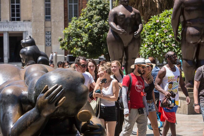 A group of people walking near large bronze sculptures in an urban setting. 5
