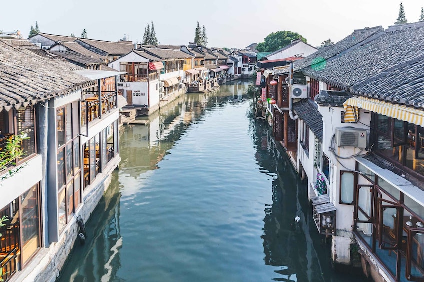 A narrow waterway flanked by traditional buildings with tiled roofs and wooden balconies. 4