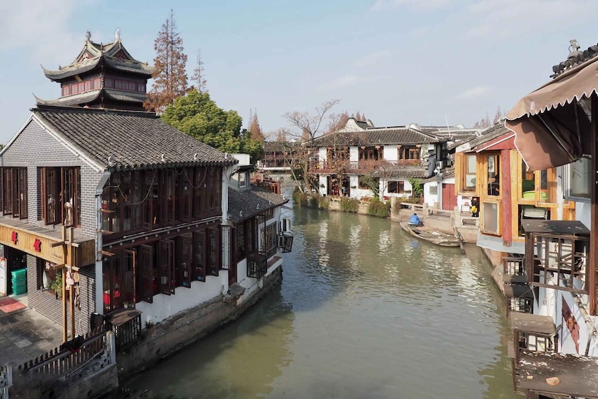 A traditional Chinese water town with narrow canals, wooden buildings, and a boat on the water. 1