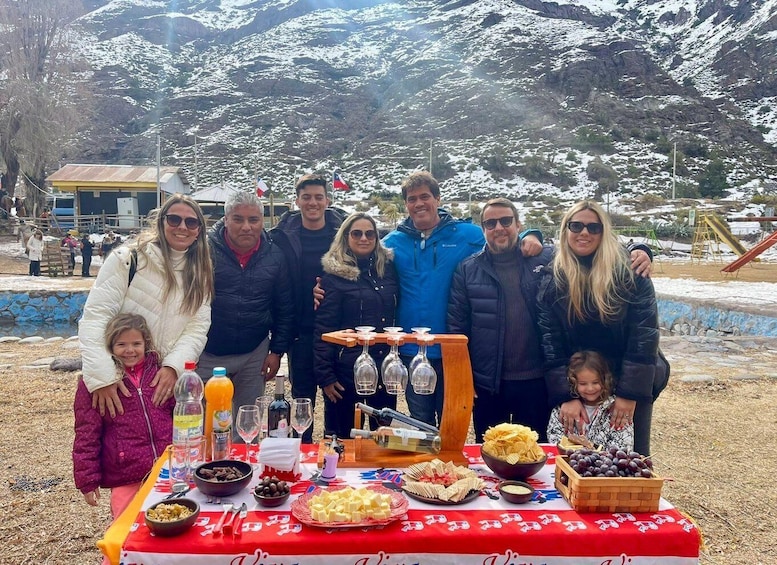 A group of people gathered around a picnic table with food and drinks in a snowy mountainous area. 5
