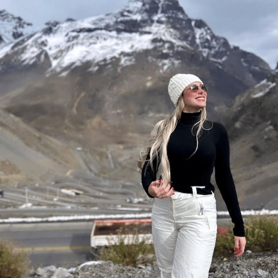 A person standing outdoors with a mountainous landscape in the background. 2