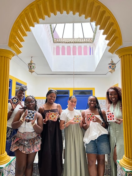 A group of people holding patterned boxes in a brightly colored room with yellow columns and a skylight. 3