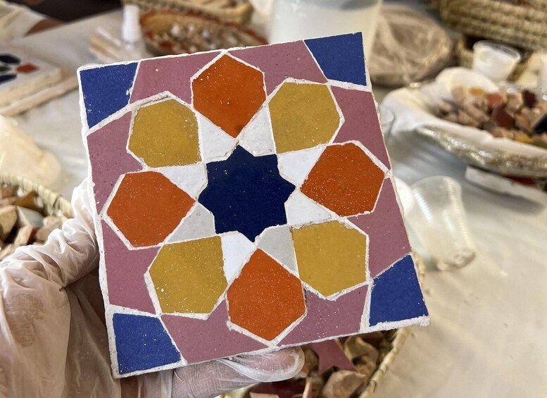 A hand holding a colorful mosaic tile with a star pattern. 4