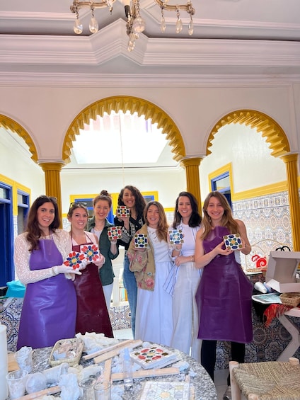A group of people holding patterned boxes in a room with ornate arches and a chandelier. 2