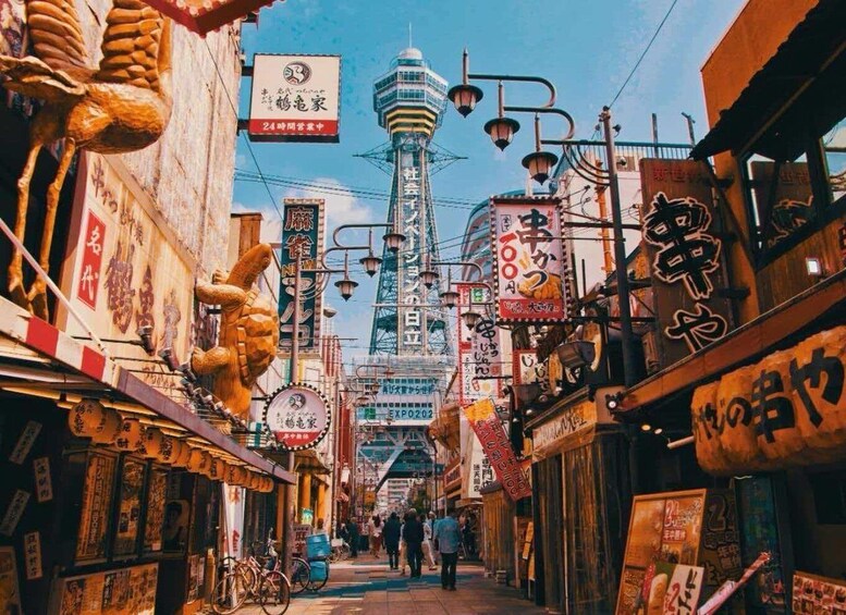 A bustling urban street with traditional signage, a prominent tower, and bicycles parked along the sidewalk. 1