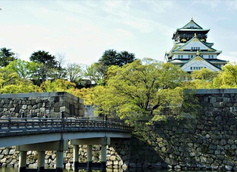 A traditional Japanese castle with a multi-tiered roof, a stone bridge, and lush greenery. 3