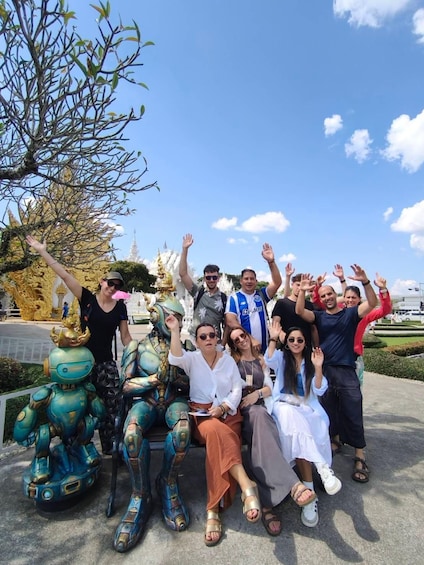 A group of people posing with a statue of a robot. 5