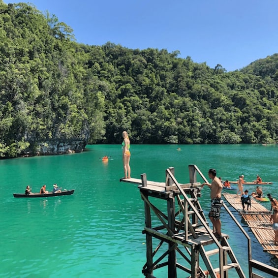 A wooden dock extending into a turquoise lake surrounded by dense forest. 4