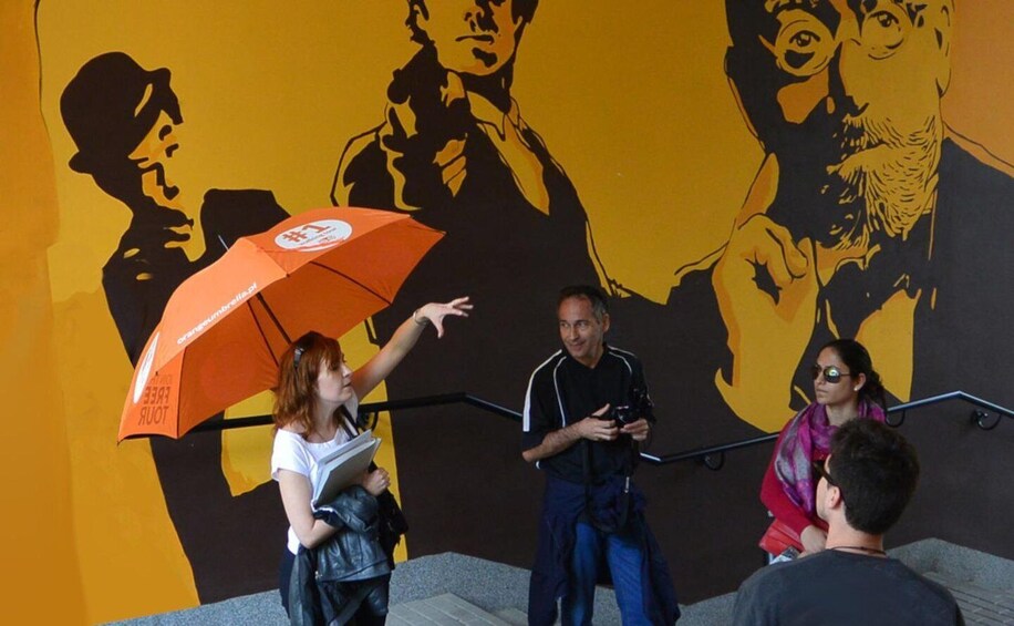 A mural with abstract human figures and a person holding an orange umbrella. 1