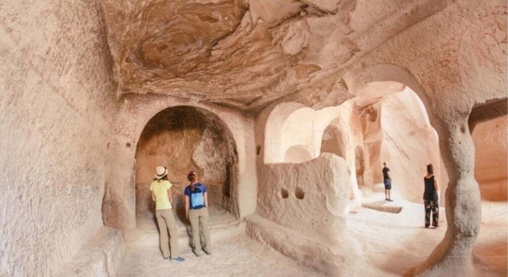 A cave with natural rock arches and a group of people standing inside. 2