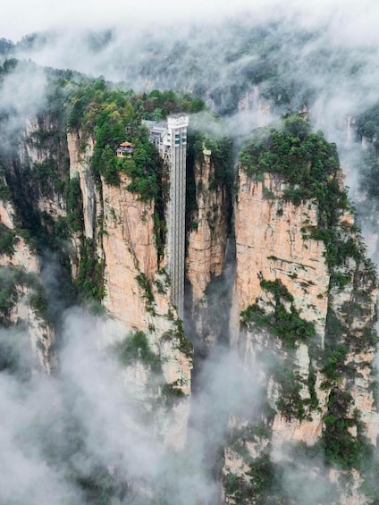 A tall tower on a cliff surrounded by dense forest and mist. 1