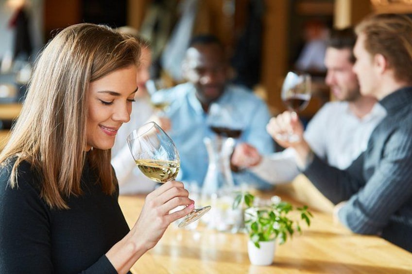 Una persona sosteniendo una copa de vino, sentada en una mesa con otras personas, en un restaurante. 1