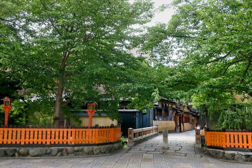 A traditional Japanese garden with stone pathways, wooden fences, and lush greenery. 2