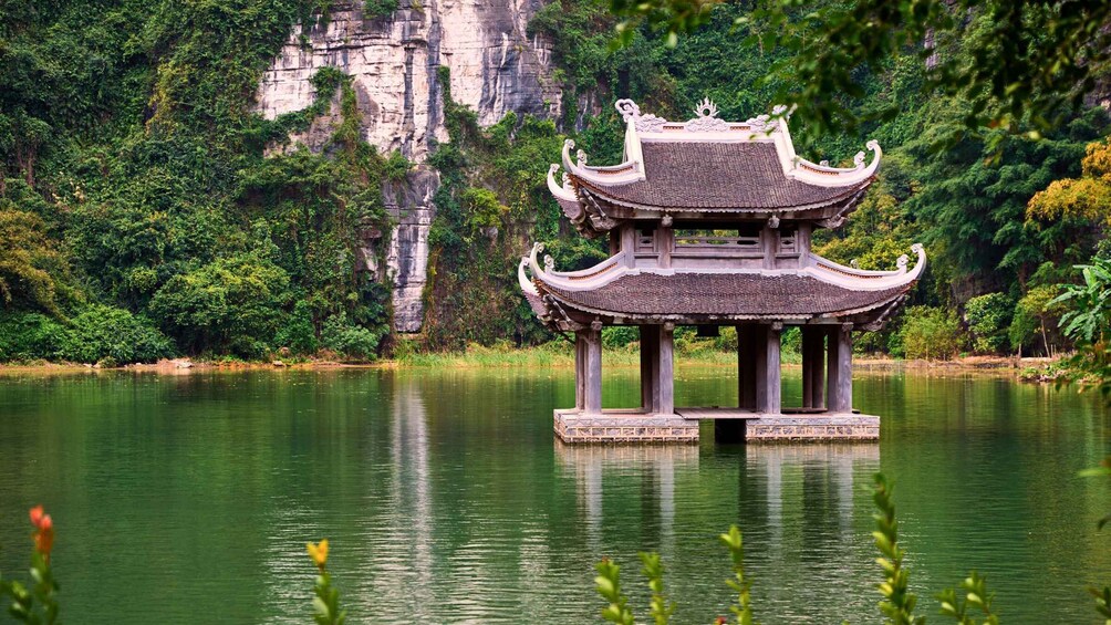 A traditional Chinese pavilion on a lake with a rocky cliff in the background. 5