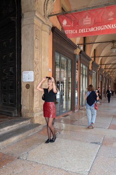 A woman adjusting her sunglasses on a stone-paved street with a red banner overhead. 3
