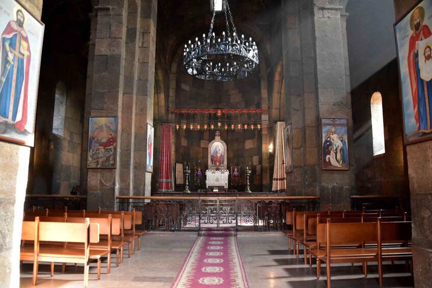 An interior of a church with wooden pews, a central altar, and a chandelier. 5