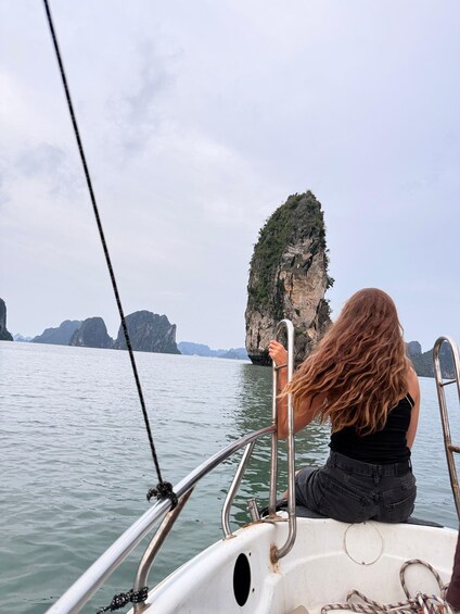 A person on a boat with a view of a large rock formation in the water. 2