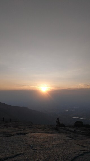 A sunset over a mountainous landscape with a fence in the foreground. 1