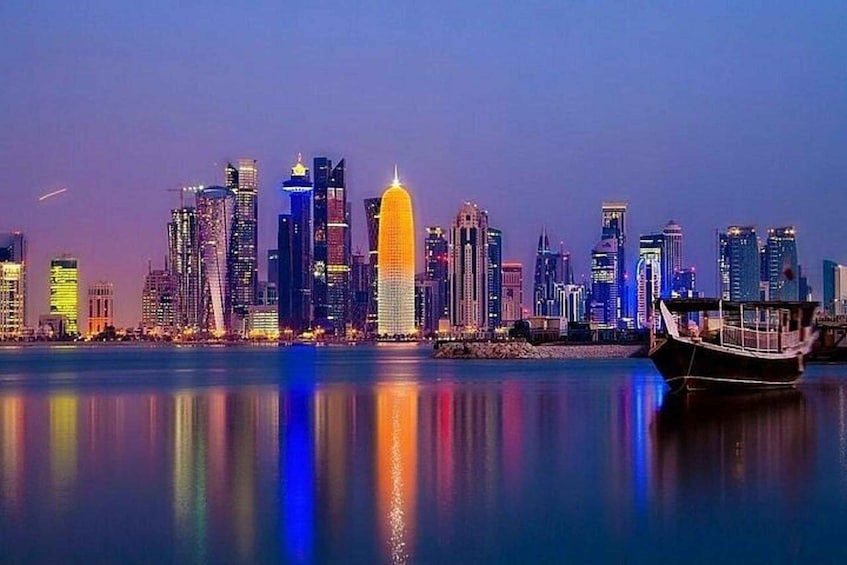 A city skyline at dusk with illuminated buildings reflecting on the water. 1