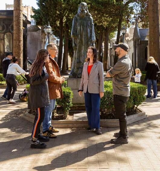 People standing and conversing in a public square with a statue in the background. 3