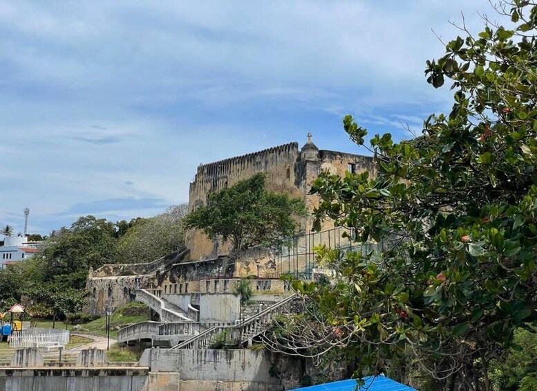 A historic fort with a watchtower, surrounded by greenery and a bridge. 3