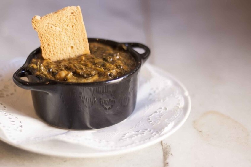 A black pot with a piece of bread on top, placed on a white plate. 5