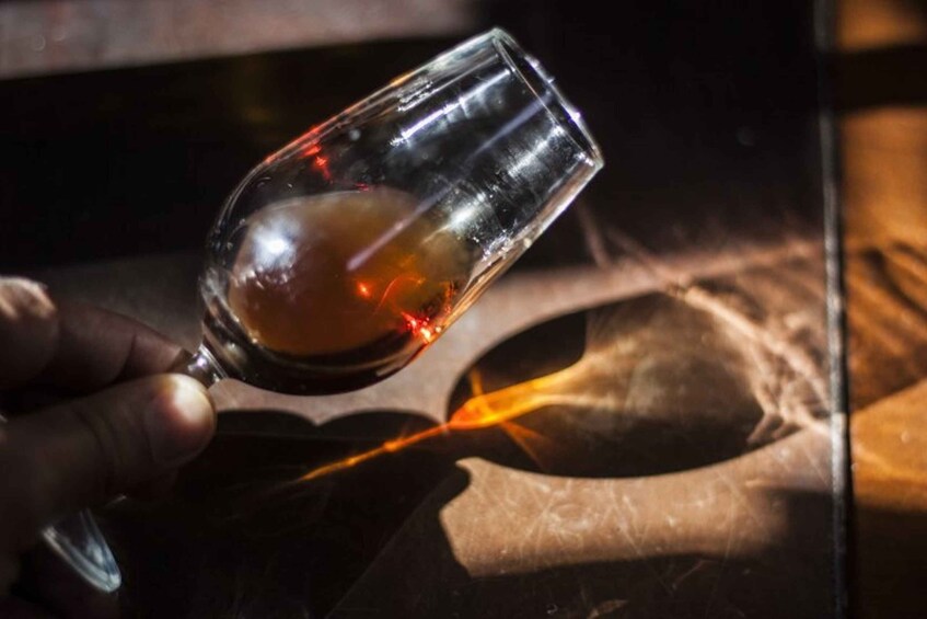 A hand holding a glass with a liquid, possibly a drink, and a flame in the background. 4