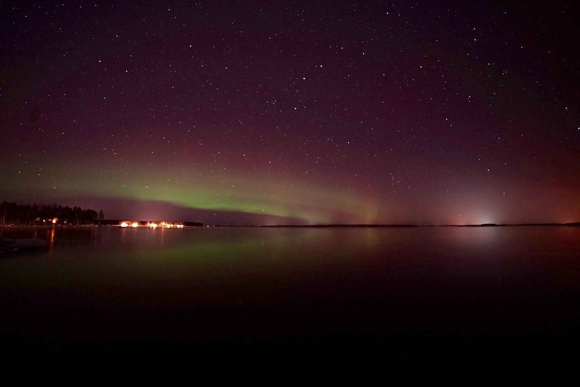A night sky with stars and the aurora borealis over a calm body of water. 1