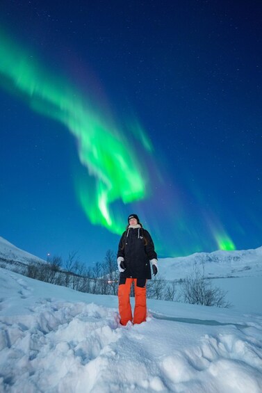 A person standing in snow with the Northern Lights in the sky. 2