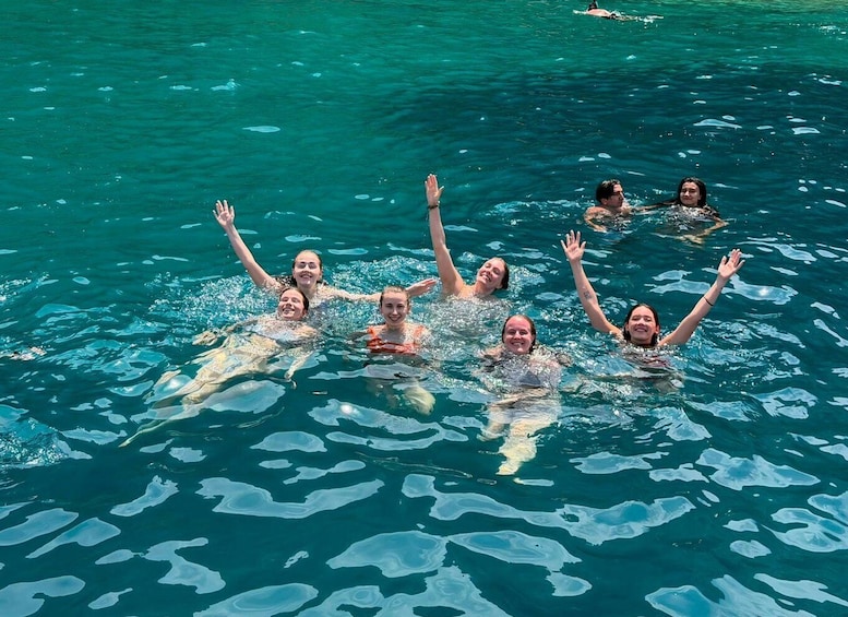 A group of people swimming in clear blue water with icebergs visible. 3