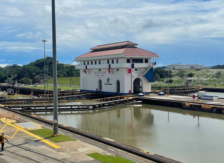 Ein Schleusenbahnhof am Panamakanal mit einem weißen Gebäude, einem roten Dach und einer Flagge. 5