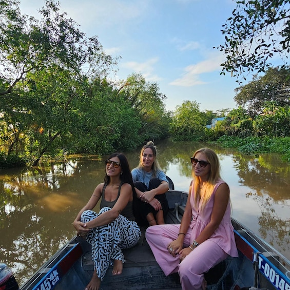 Three people on a boat in a river surrounded by dense foliage. 2