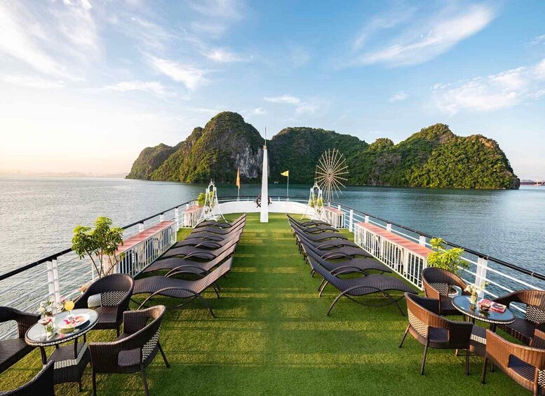 A deck with lounge chairs and tables overlooking a body of water with islands in the distance. 2