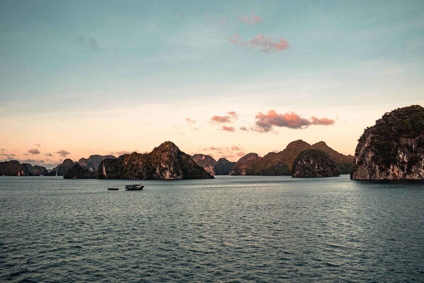 A calm sea with a boat in the foreground and limestone islands in the background. 3