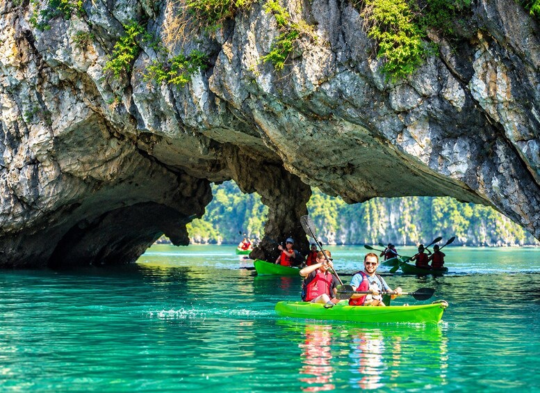 People kayaking in a turquoise river under a large rock formation. 4