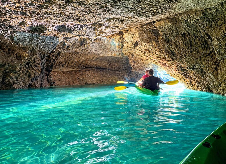 A person kayaking inside a cave with clear turquoise water. 1