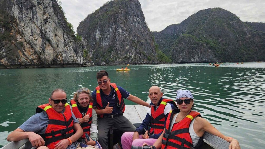 A group of people on a boat with rocky cliffs in the background. 5
