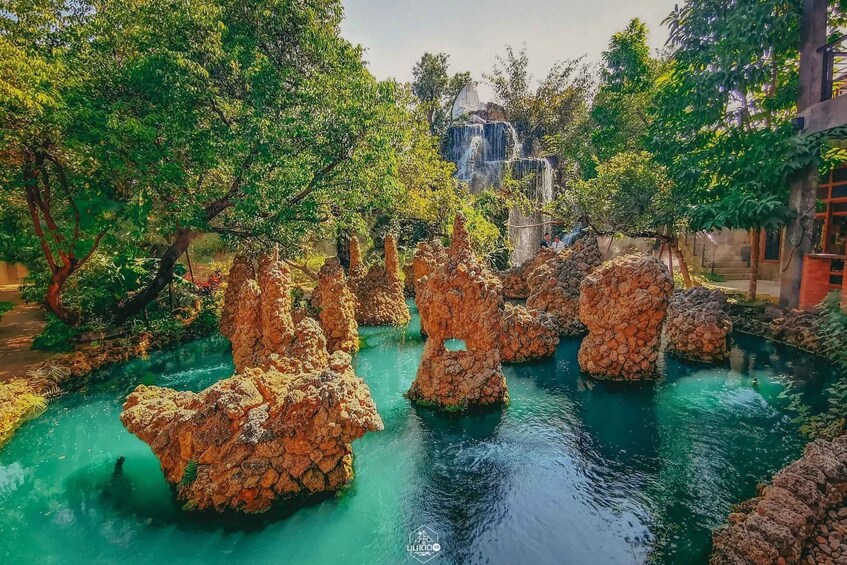 A serene water feature with rock formations and a waterfall in the background. 4
