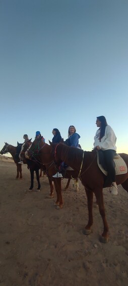 A group of people riding horses in a desert landscape. 1
