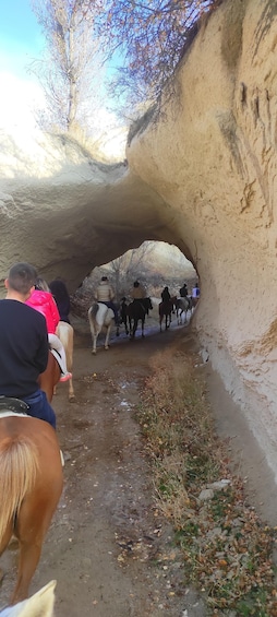 People riding horses through a rocky tunnel. 4