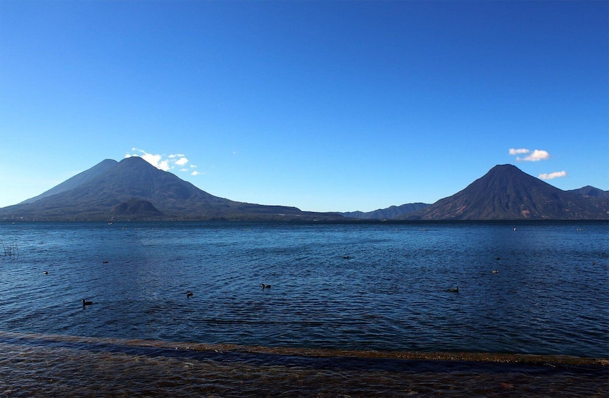 A calm lake with two prominent mountains in the background. 1