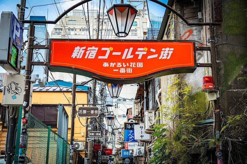 A street sign with Japanese characters, a green fence, and various utility poles. 3