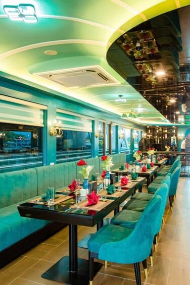 A restaurant with teal seating, tables set with red napkins and vases. 4